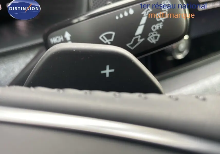 Gros plan sur la palette de changement de vitesse "+" derrière le volant d'un Skoda Kamiq noir magique métal, intérieur sombre.