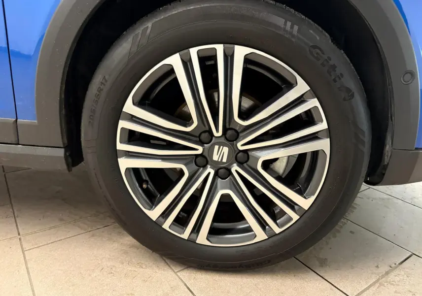 Gros plan sur la roue avant droite du SEAT Arona bleu saphir avec jante alliage bicolore et logo central.