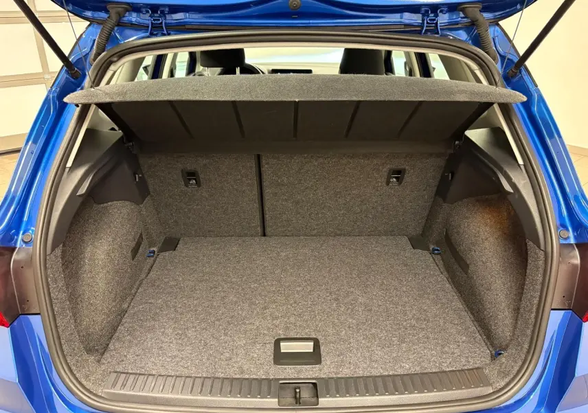 Coffre ouvert d’un SEAT Arona Bleu Saphir, vue arrière montrant l’espace de chargement vide et la tablette cache-bagages relevée.