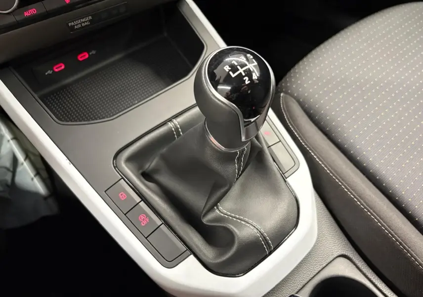 Gros plan sur la commande de la boîte manuelle noire avec coutures blanches dans l’habitacle du SEAT Arona 2025.