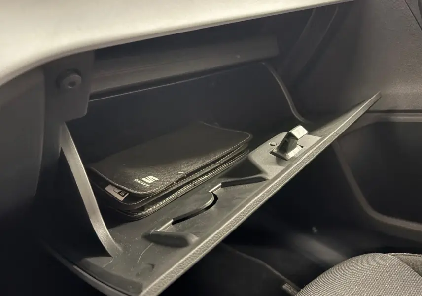 Gant de boîte à gants ouvert côté passager avec pochette noire SEAT visible à l'intérieur, intérieur sombre.