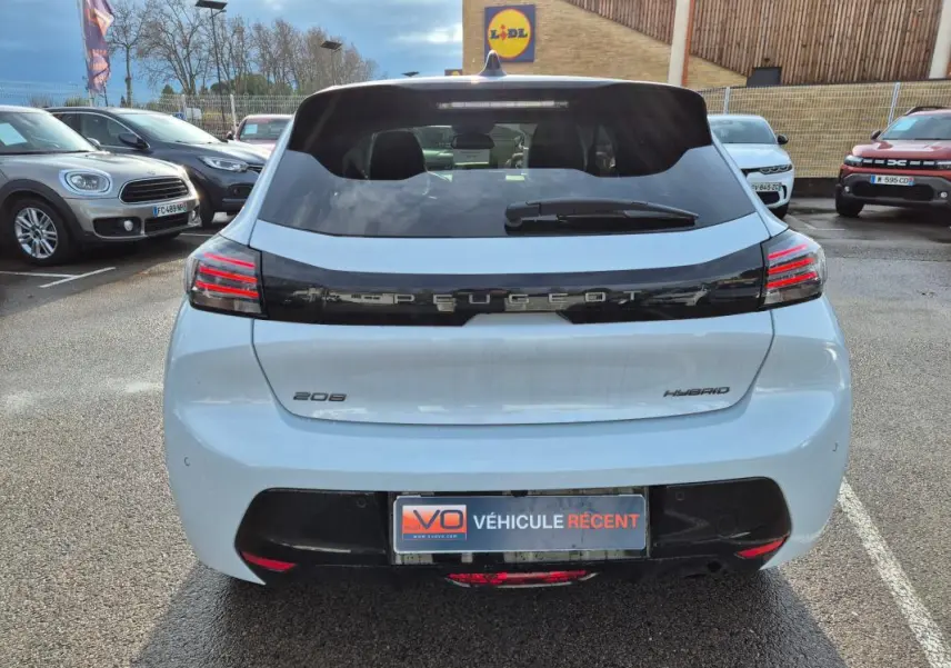 Vue arrière d'une Peugeot 208 Hybrid blanche 2025 avec feux LED et logo Peugeot noir brillant.