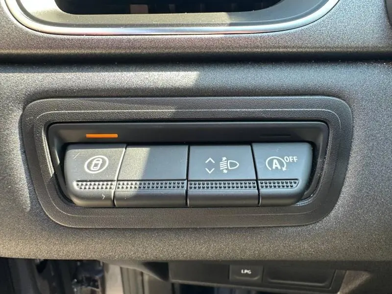 Gros plan sur les commandes de réglage des phares et de désactivation du démarrage auto du Renault Captur gris Cassiopée métallisé.