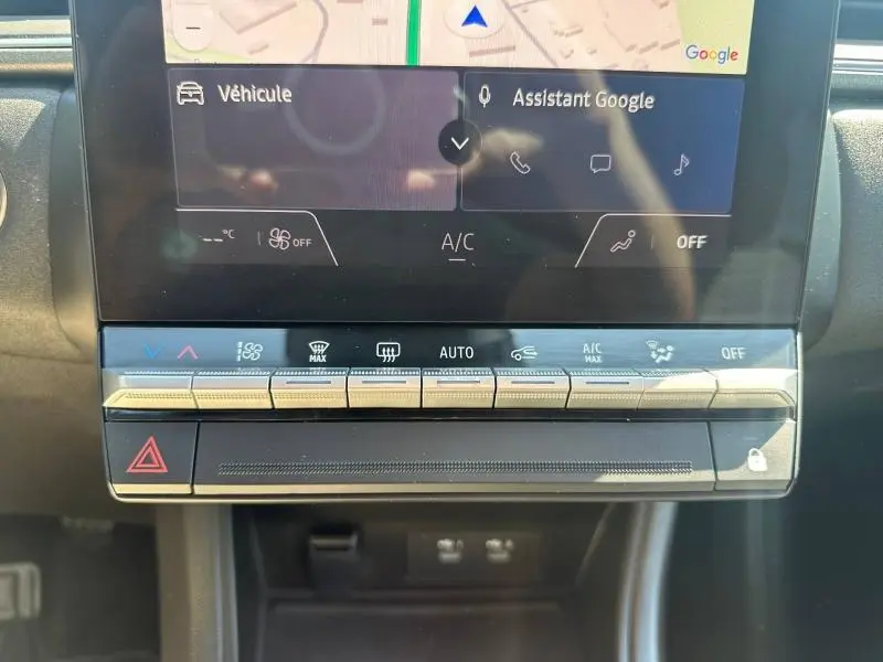 Gros plan sur la console centrale tactile du Renault Captur 2025 avec commandes climatisation et assistant Google visible.