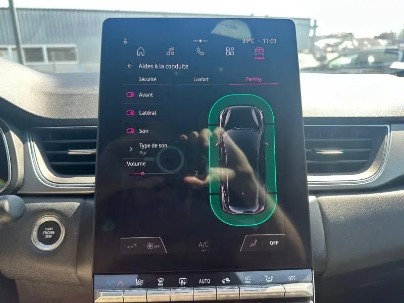 Écran tactile central du Renault Captur 2025 montrant l'aide au stationnement avec vue top-down du véhicule gris métallisé.