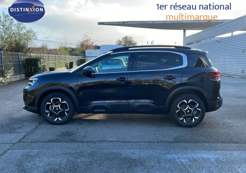 Vue de profil côté gauche d'un Citroën C5 Aircross 2025 noir Perla Metal avec jantes bi-ton et barres de toit.