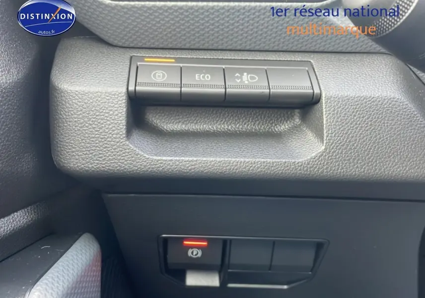 Détail intérieur côté conducteur du Dacia Duster 2026, montrant les boutons de contrôle de l'éclairage et frein à main électronique.