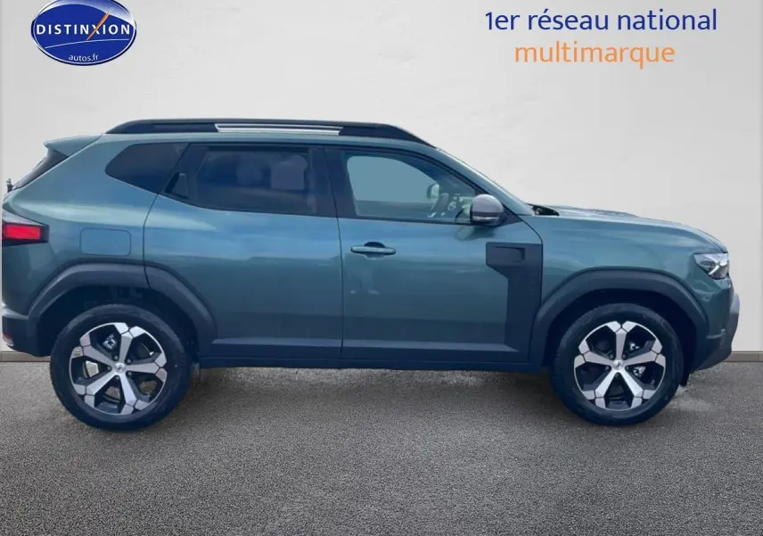 Profil droit du Dacia Duster 2026 vert cèdre avec jantes alliage et barres de toit noires.
