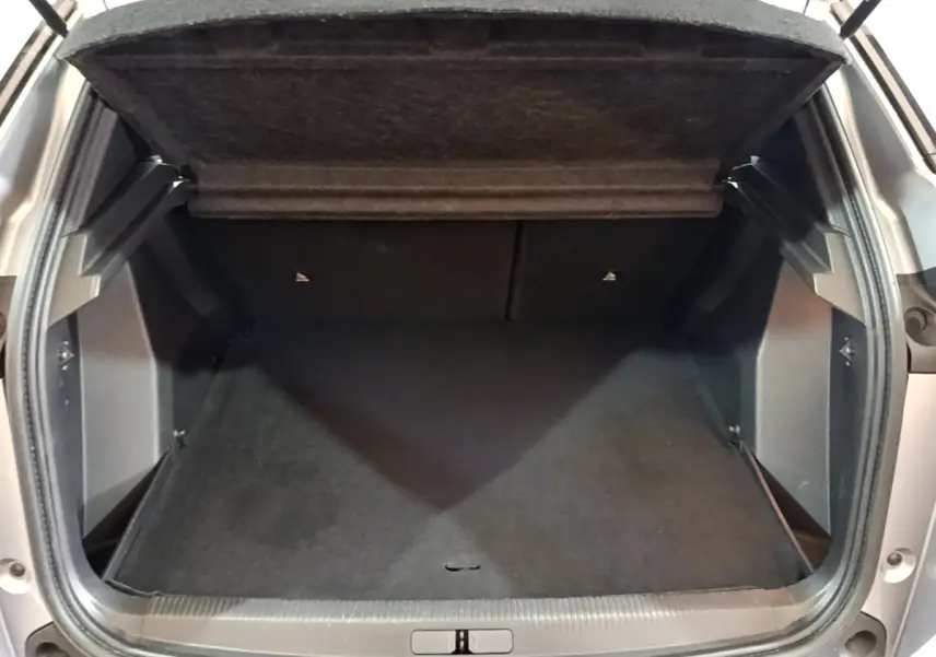 Coffre ouvert vu de face d’un Peugeot 2008 gris clair, montrant l’espace de chargement vide et la tablette arrière relevée.