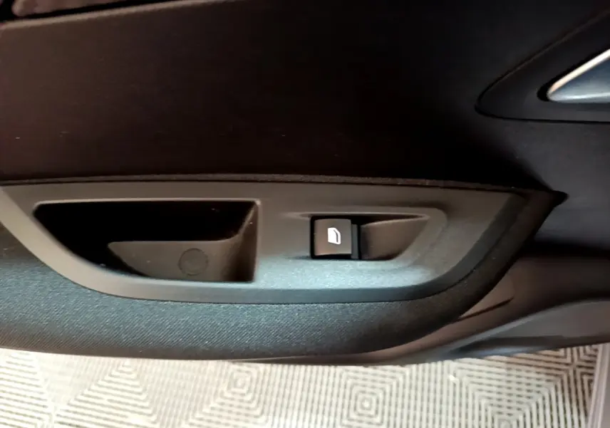 Détail de la commande de lève-vitre sur la porte intérieure côté conducteur d’un Peugeot 2008 gris clair 2021.