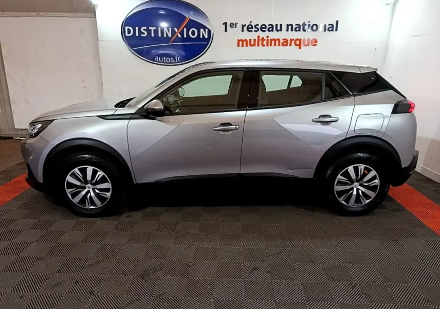 Profil droit d'un Peugeot 2008 gris clair 2021 garé en intérieur avec jantes alliage et toit noir contrasté.