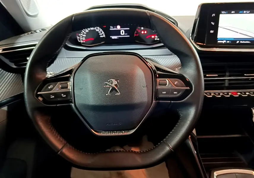 Vue rapprochée du volant cuir noir de la Peugeot 2008 2021 avec tableau de bord numérique et écran tactile central.