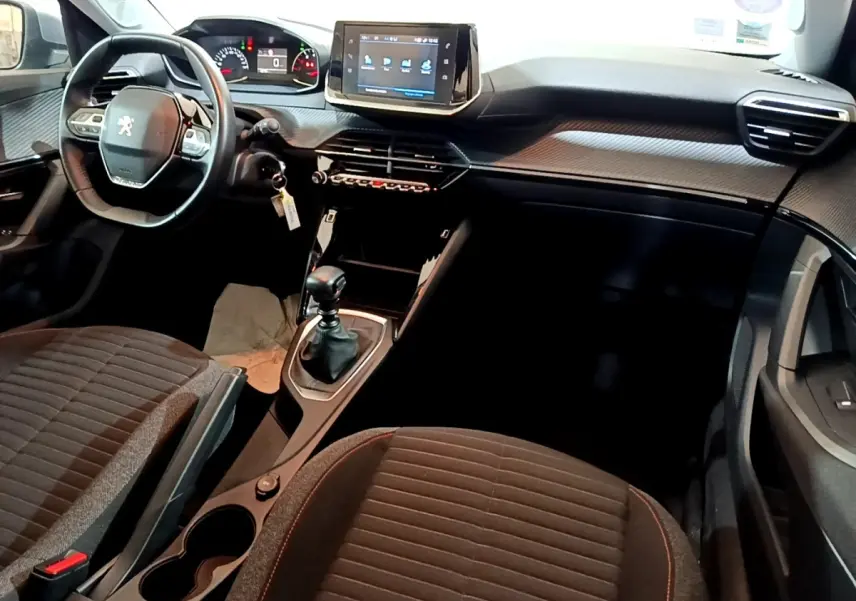 Vue intérieure avant du Peugeot 2008 gris clair 2021, montrant le volant cuir, écran tactile central et boîte manuelle.