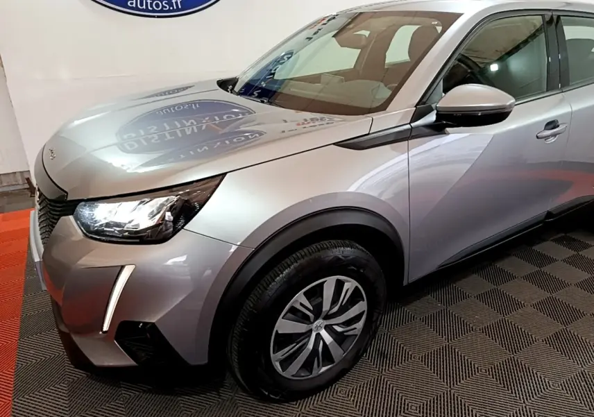 Vue 3/4 avant droit d'un Peugeot 2008 gris clair avec phares LED et jantes alliage distinctives.