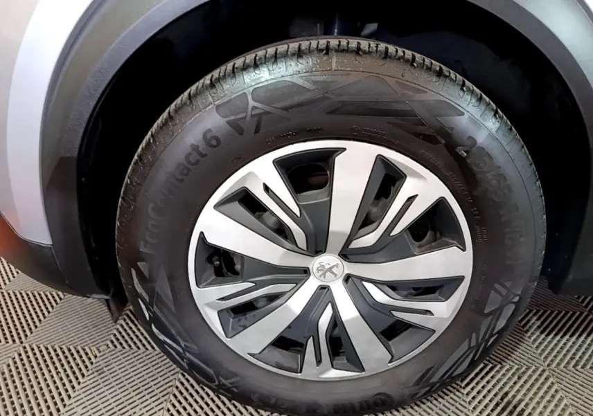 Gros plan sur la roue avant droite d’un Peugeot 2008 gris clair, avec jante en alliage au design moderne.