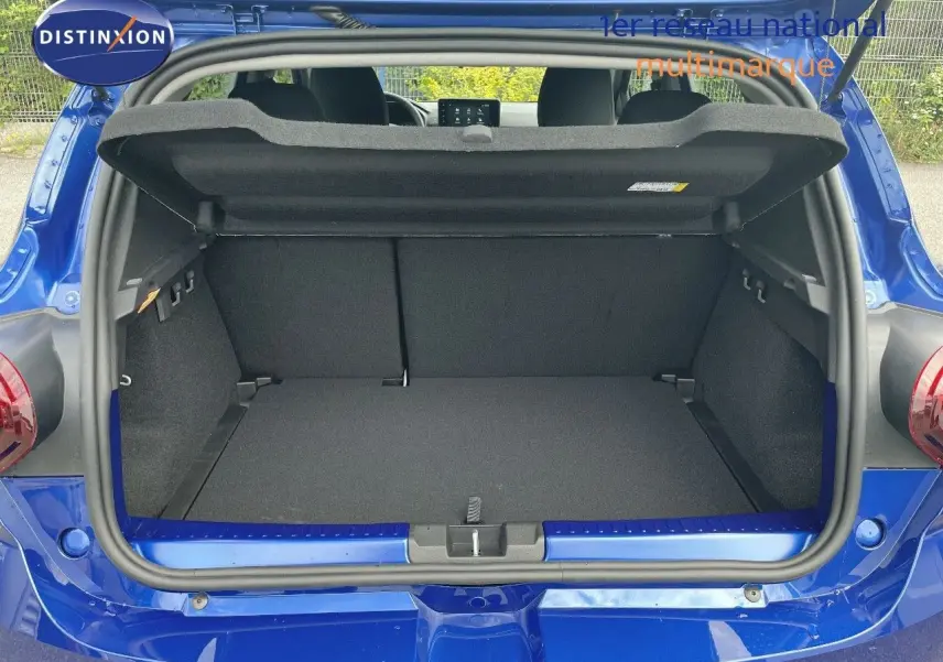 Coffre ouvert d'une Dacia Sandero Stepway 2024 bleu iron metal, vue arrière montrant l'espace de chargement vide.