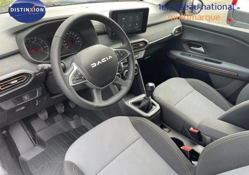 Vue intérieure côté conducteur de la Dacia Sandero Stepway 2024, avec volant multifonction et sellerie gris clair.