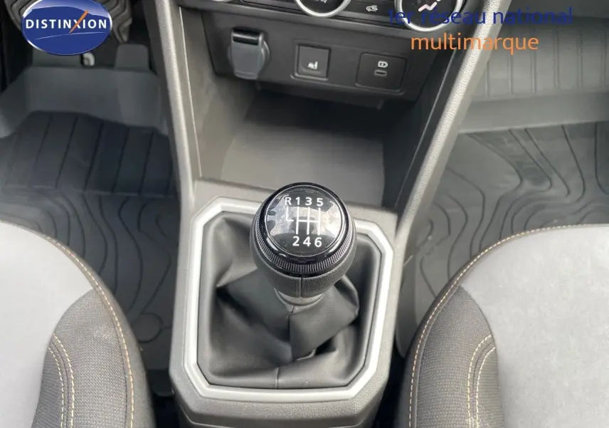 Le levier de vitesses manuel de la DACIA SANDERO STEPWAY 2024, entouré de sièges gris et noir avec surpiqûres beige.