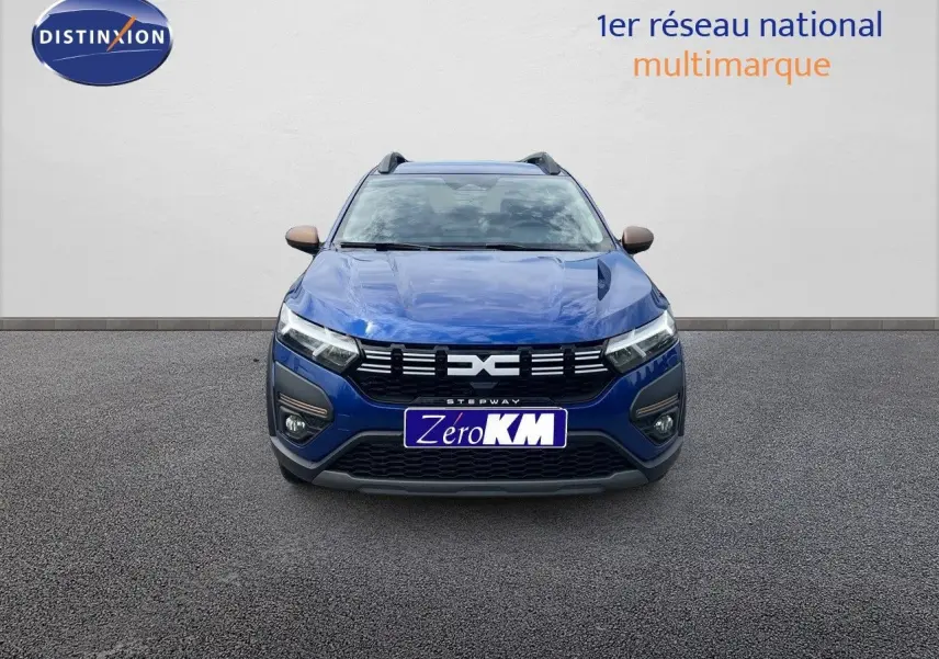 Vue frontale d'une Dacia Sandero Stepway 2024 en bleu Iron Metal avec calandre noire et phares LED allumés.