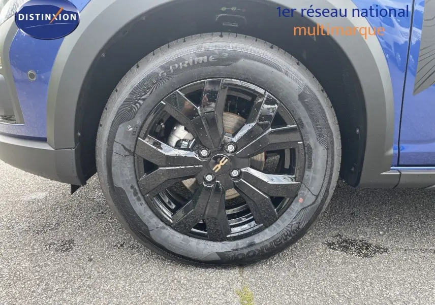 Gros plan sur la roue avant gauche noire brillante du Dacia Sandero Stepway bleu Iron Metal 2024.