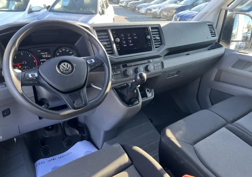 Intérieur du Volkswagen Crafter 35 L3H3 Business 2022, vue de face sur le poste de conduite et la banquette double grise.