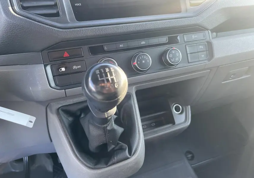 Gros plan sur la commande de boîte manuelle et la console centrale noire du Volkswagen Crafter Fourgon blanc de 2022.