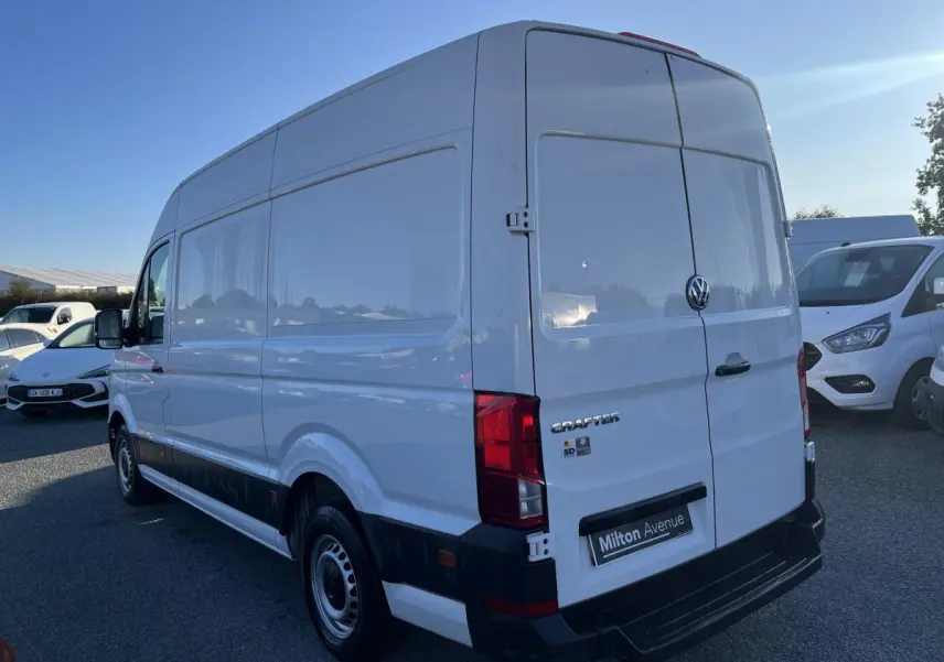 Vue 3/4 arrière droite d'un Volkswagen Crafter fourgon blanc avec portes battantes et jantes acier argentées.