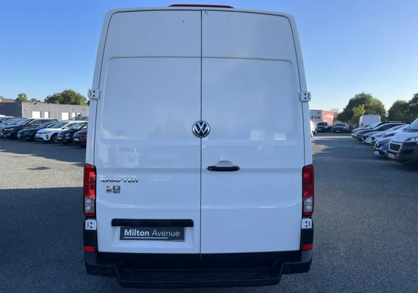 Vue arrière d'un utilitaire Volkswagen Crafter blanc avec portes battantes et logo central visible.