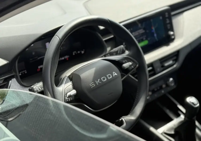 Intérieur de la Skoda Scala TSI 116 gris graphite, vue rapprochée du volant cuir multifonctions et levier de vitesse manuel.