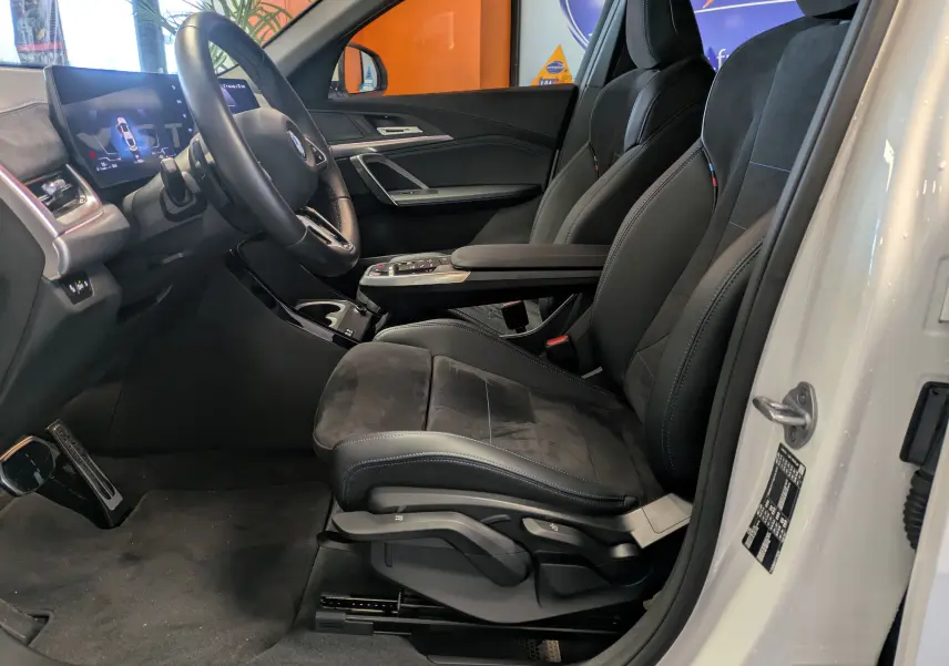 Gros plan sur les commandes d'éclairage automatiques du BMW X2 sDrive blanc, avec bouton auto allumé sous le tableau de bord.