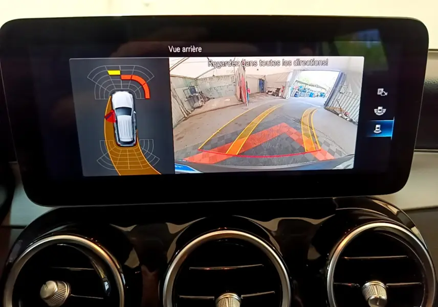 Écran tactile intérieur affichant la caméra de recul et les capteurs de stationnement du Mercedes GLC hybride gris foncé.