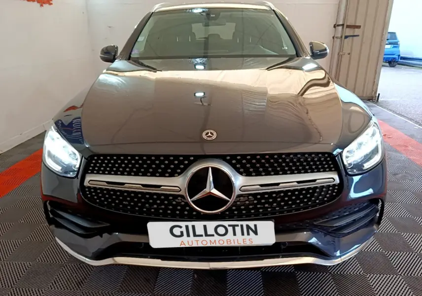 Vue frontale d'un Mercedes GLC 300 E AMG Line gris foncé avec phares LED allumés et calandre distinctive.