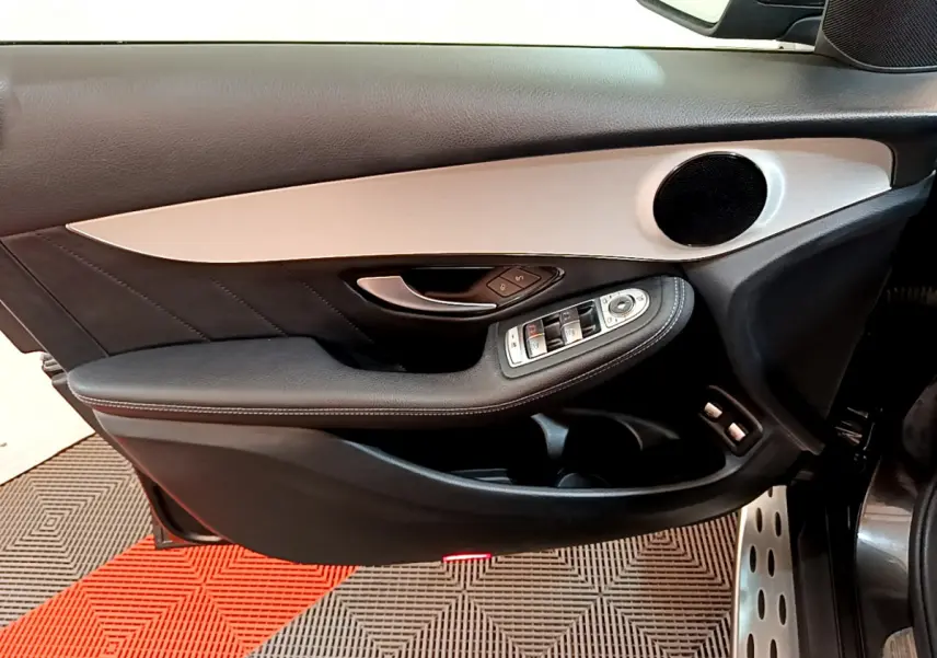 Gros plan sur la porte avant gauche noire et grise du Mercedes GLC 300 E AMG Line avec commandes électriques et haut-parleur rond.