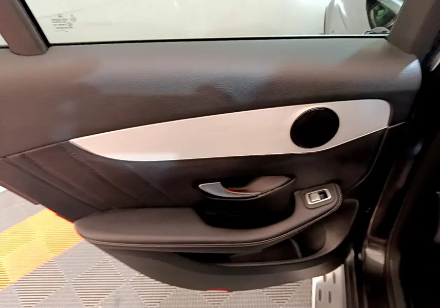 Vue rapprochée de la porte intérieure côté droit du Mercedes GLC 300 E AMG Line gris foncé avec garniture noire et insert argenté.