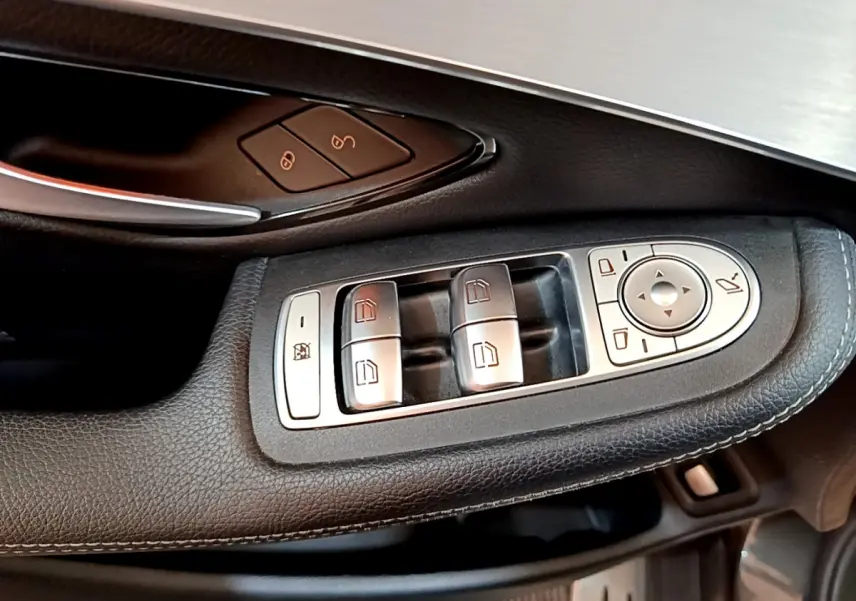 Gros plan sur les commandes de lève-vitres et réglages des rétroviseurs côté conducteur en cuir noir du Mercedes GLC gris foncé
