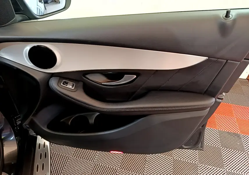 Vue rapprochée de la porte avant gauche gris foncé du Mercedes GLC 300 E AMG Line avec insert aluminium et commande de vitre.