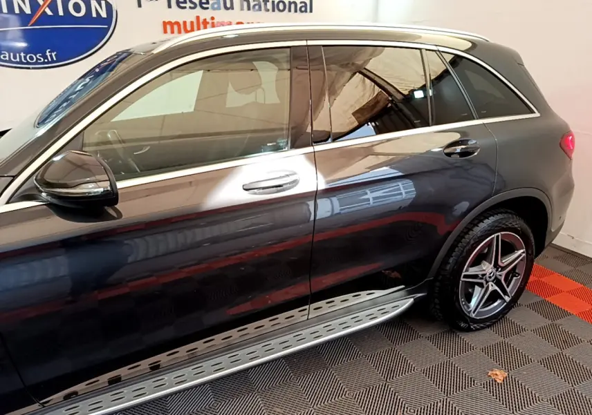 Vue latérale côté gauche d'un Mercedes GLC 300 E AMG Line gris foncé avec jantes AMG et marchepieds métalliques.