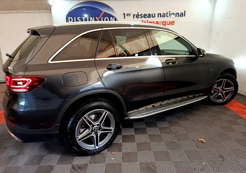 Vue de profil côté droit d'un Mercedes GLC 300 E AMG Line gris foncé avec jantes alliage et feux arrière allumés.