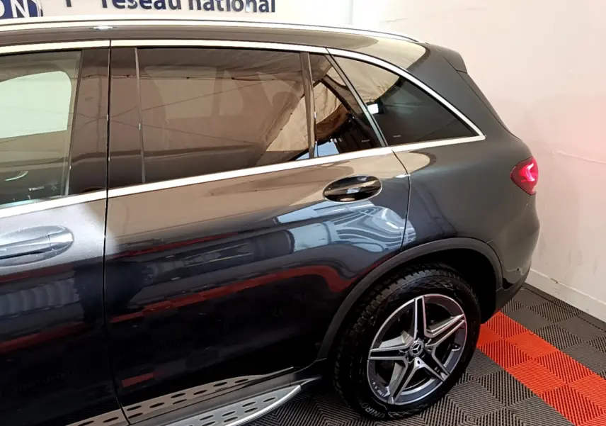 Vue latérale arrière droite d'un Mercedes GLC 300 E AMG Line gris foncé avec jantes alliage et feux arrière LED allumés.