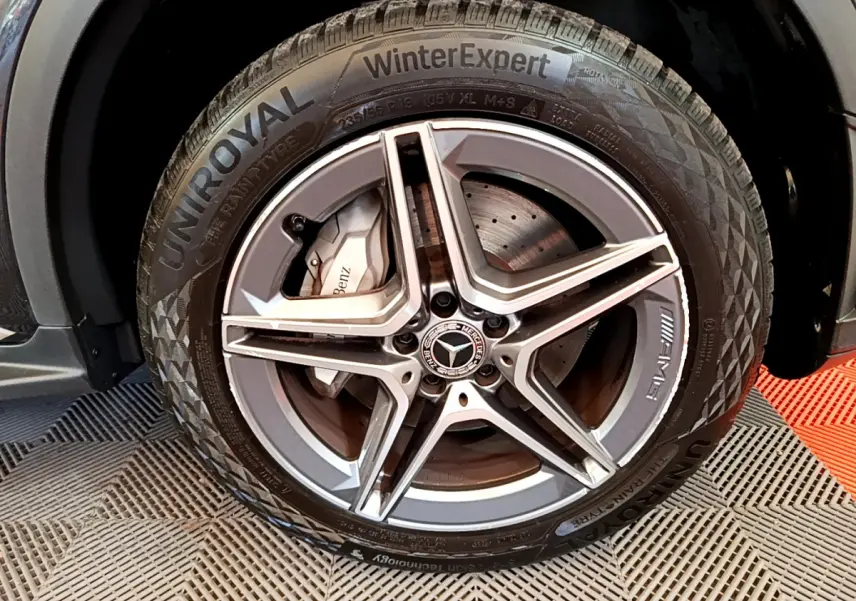 Gros plan sur la roue avant droite du Mercedes GLC 300 E AMG Line gris foncé avec jante AMG et pneu Uniroyal WinterExpert.