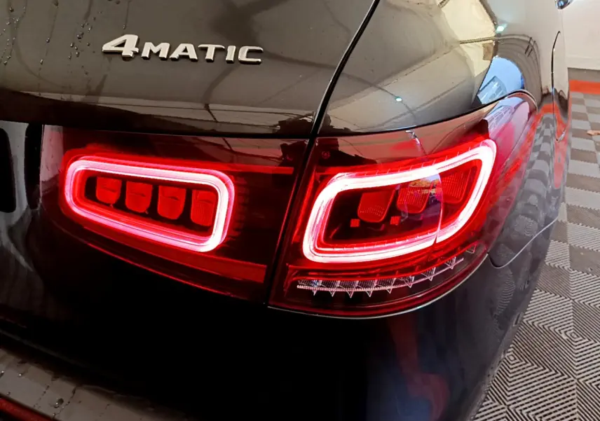 Gros plan sur le feu arrière droit rouge et le logo 4MATIC d’un Mercedes GLC 300 E AMG Line gris foncé.
