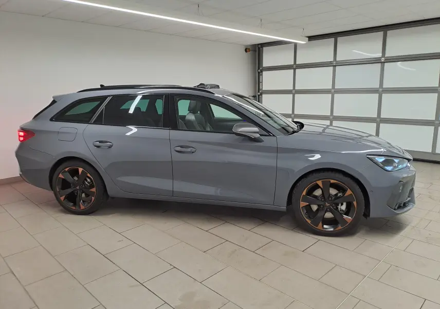 Vue de profil côté gauche d'une CUPRA Leon ST 2025 gris Graphène avec jantes cuivrées et toit ouvrant panoramique.