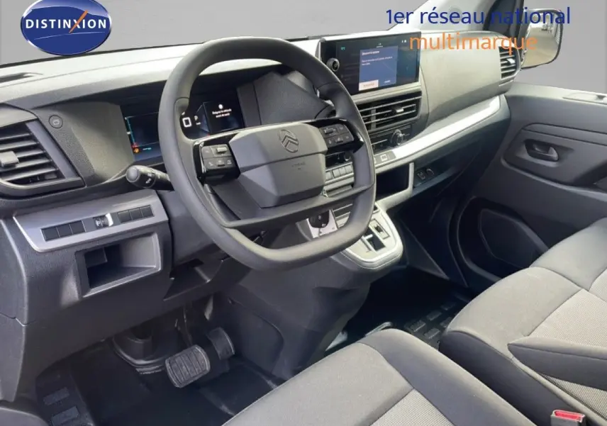 Vue intérieure côté conducteur du Citroën Jumpy gris titane, montrant le volant, tableau de bord et console centrale moderne.