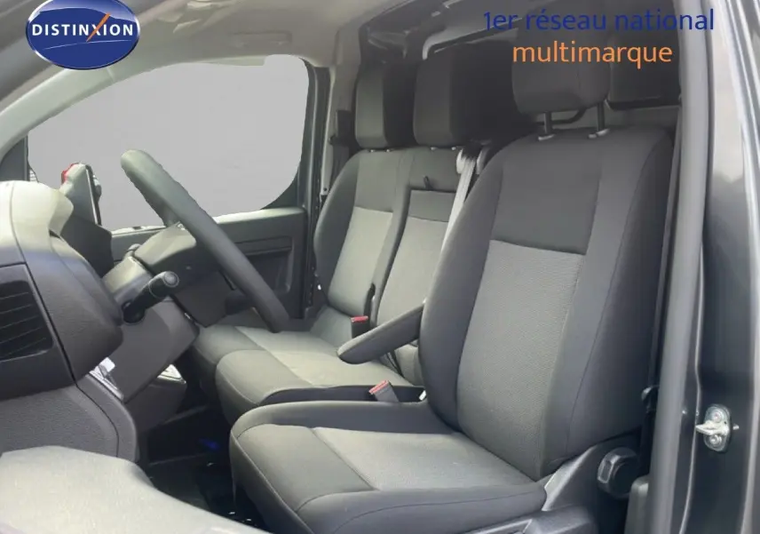 Vue intérieure côté conducteur du Citroën Jumpy gris titane, montrant les sièges avant en tissu noir et gris.