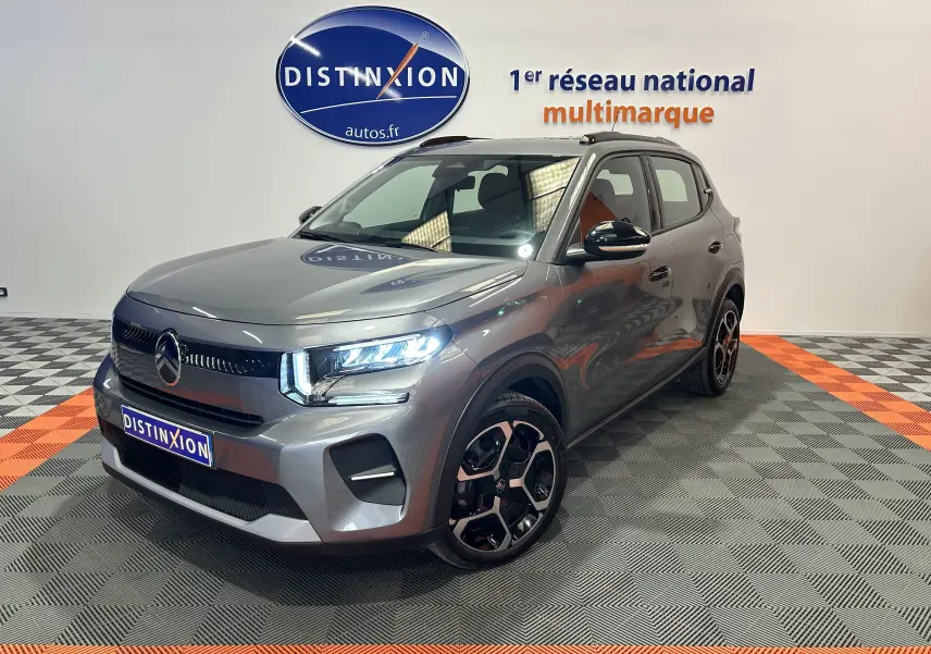 Citroën C3 Turbo 100 PLUS gris Artense en 3/4 avant droit, avec jantes bi-ton et phares LED allumés.