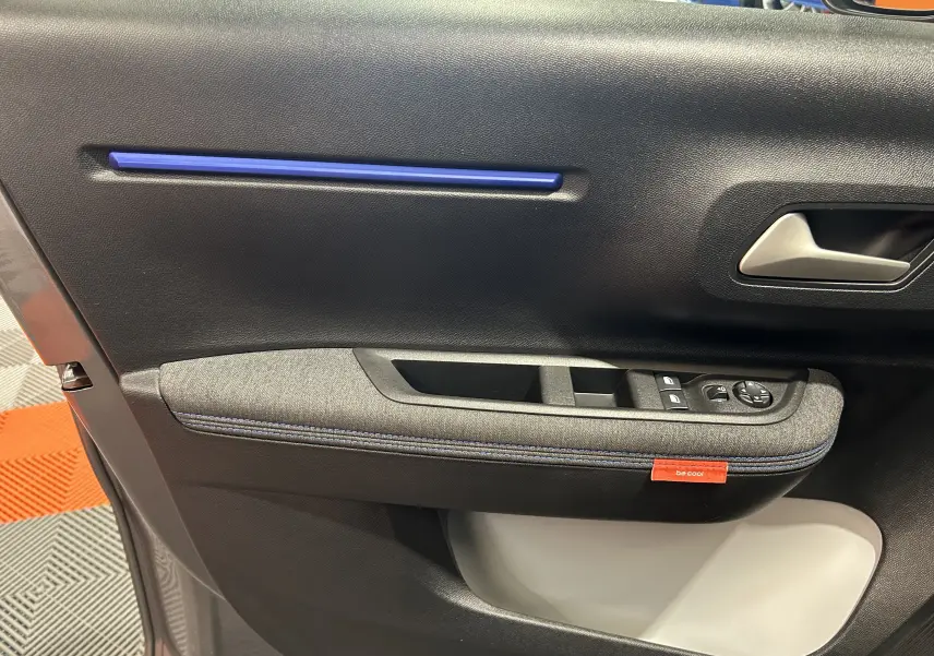 Détail de la porte intérieure côté gauche de la Citroën C3 Turbo 100 PLUS gris Artense avec insert bleu et étiquette "be cool".