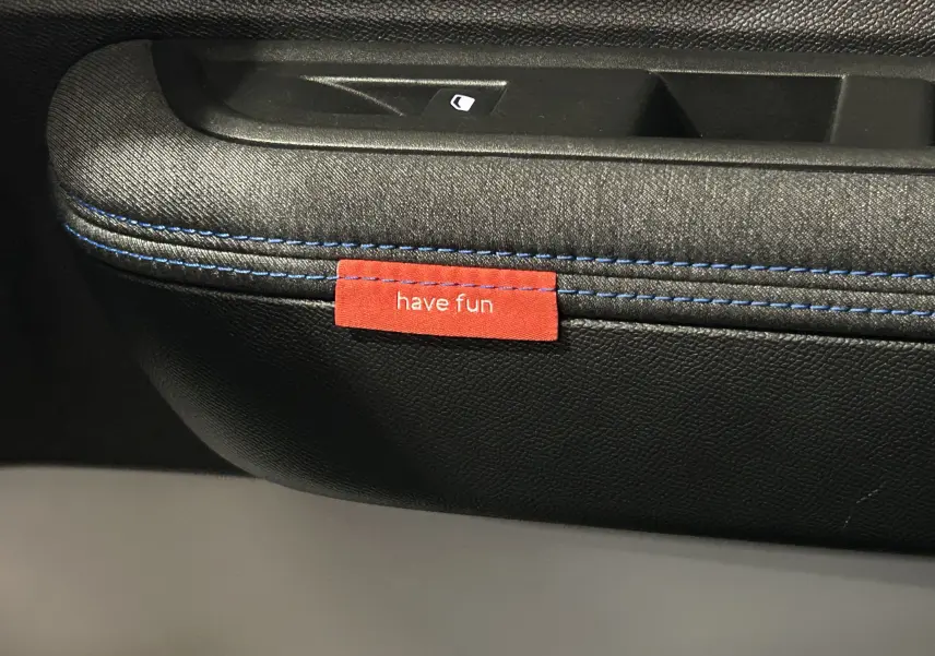 Détail de la porte intérieure côté gauche de la Citroën C3 gris Artense avec couture bleue et étiquette rouge "have fun".