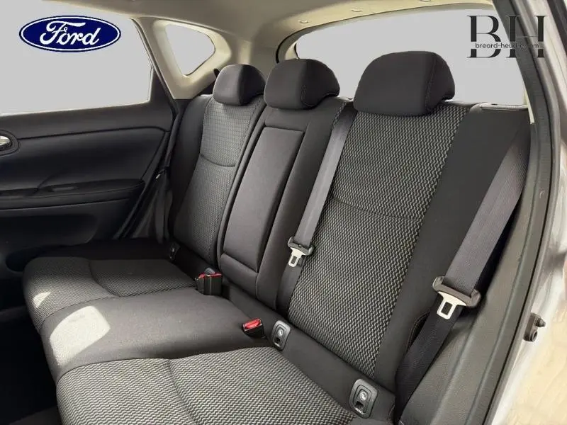 Vue intérieure de la banquette arrière noire avec ceintures de sécurité, appuie-têtes et porte arrière ouvert côté droit.