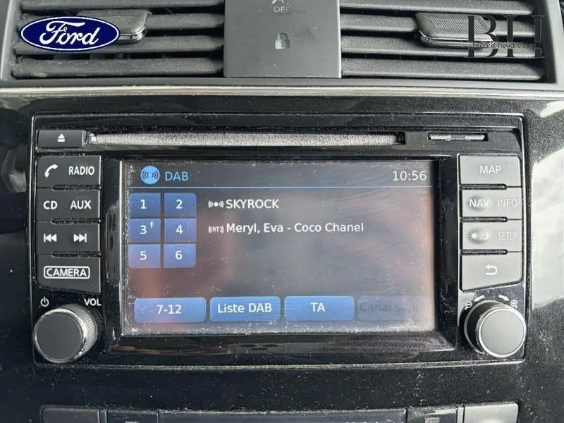 Écran tactile central d’un Nissan Pulsar bronze ultime, affichant la radio DAB sur Skyrock, vue de face rapprochée.