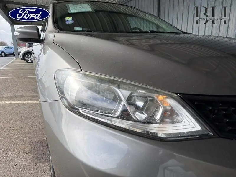 Gros plan sur le phare avant droit d'une Nissan Pulsar bronze ultime, mettant en valeur les lignes modernes du capot.